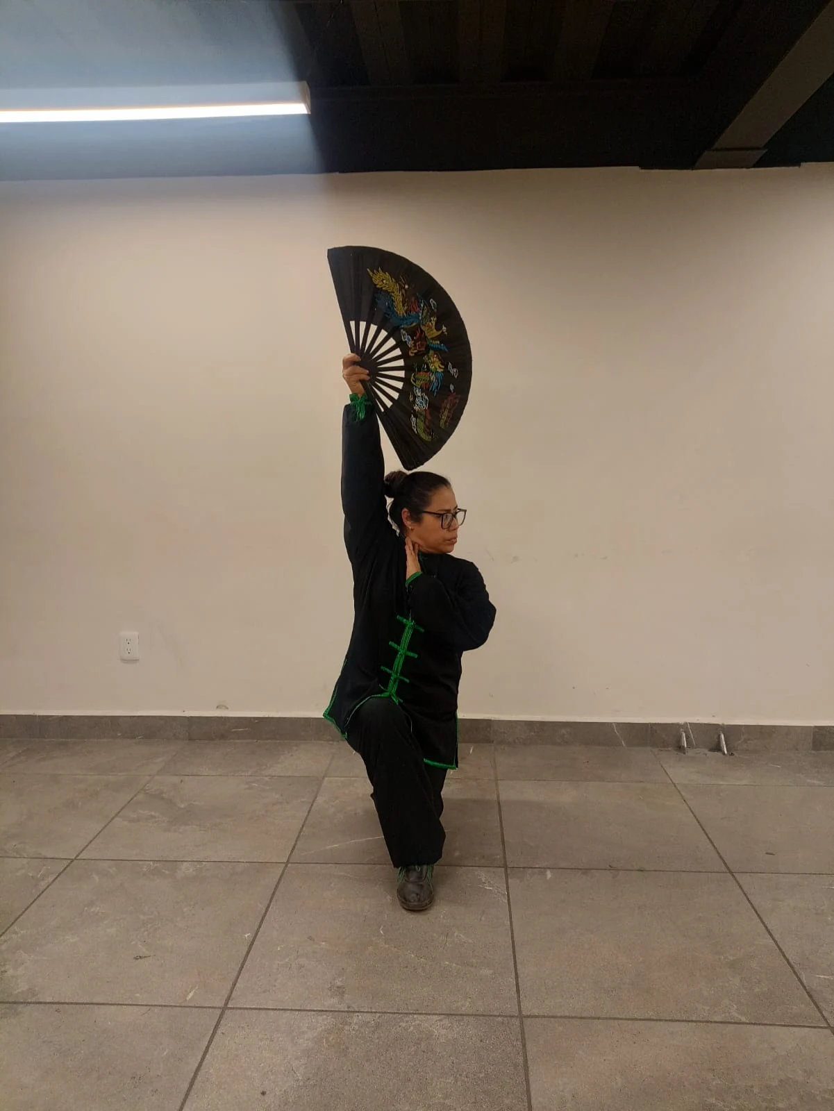 Práctica de Tai Chi con un abanico abierto y un brazo elevado